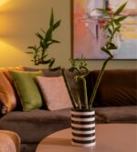 Siyah ve beyaz yatay çizgilerin ön planda olduğu modern bir vazo.