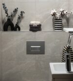 Lavabo, tuvalet ve üzerinde siyah beyaz çizgili vazo bulunan rafın yer aldığı modern bir banyo.